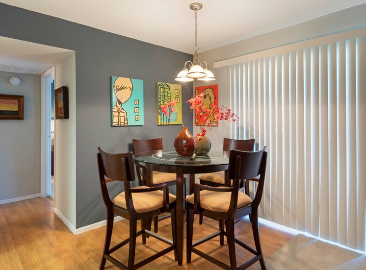 Dining Room with Hardwood Style Flooring, Blue Accent Wall with Art Next to Vertical Blinds Covering Patio Door